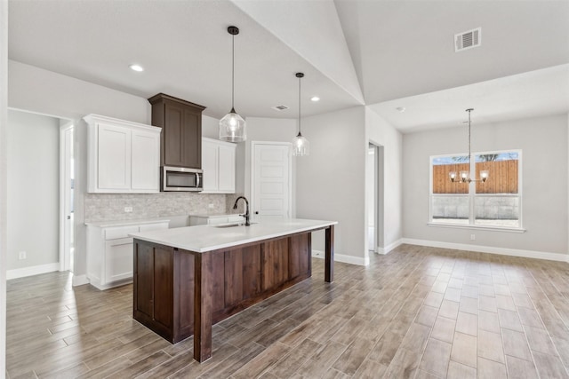 kitchen with dark brown cabinets, sink, a chandelier, hanging light fixtures, and lofted ceiling