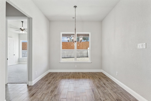 unfurnished dining area featuring ceiling fan with notable chandelier and a healthy amount of sunlight