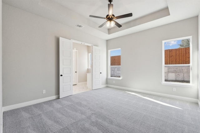 unfurnished bedroom featuring a raised ceiling, ceiling fan, and light colored carpet