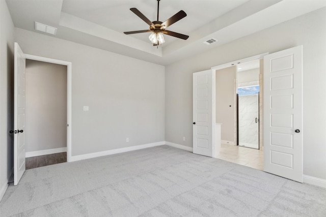 unfurnished bedroom with a tray ceiling, ceiling fan, and light colored carpet