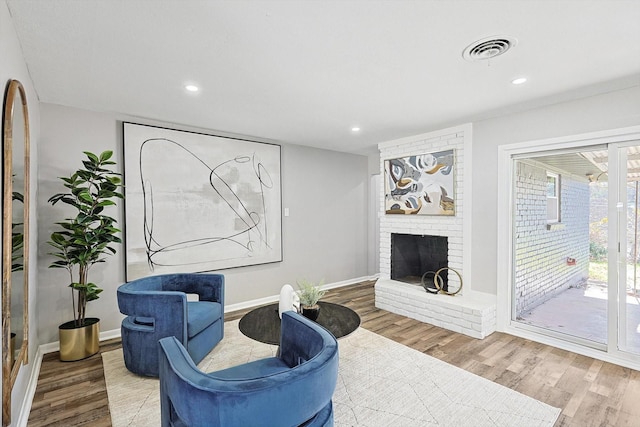 living area featuring hardwood / wood-style flooring and a brick fireplace