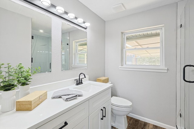 bathroom featuring hardwood / wood-style flooring, vanity, toilet, and a shower with shower door