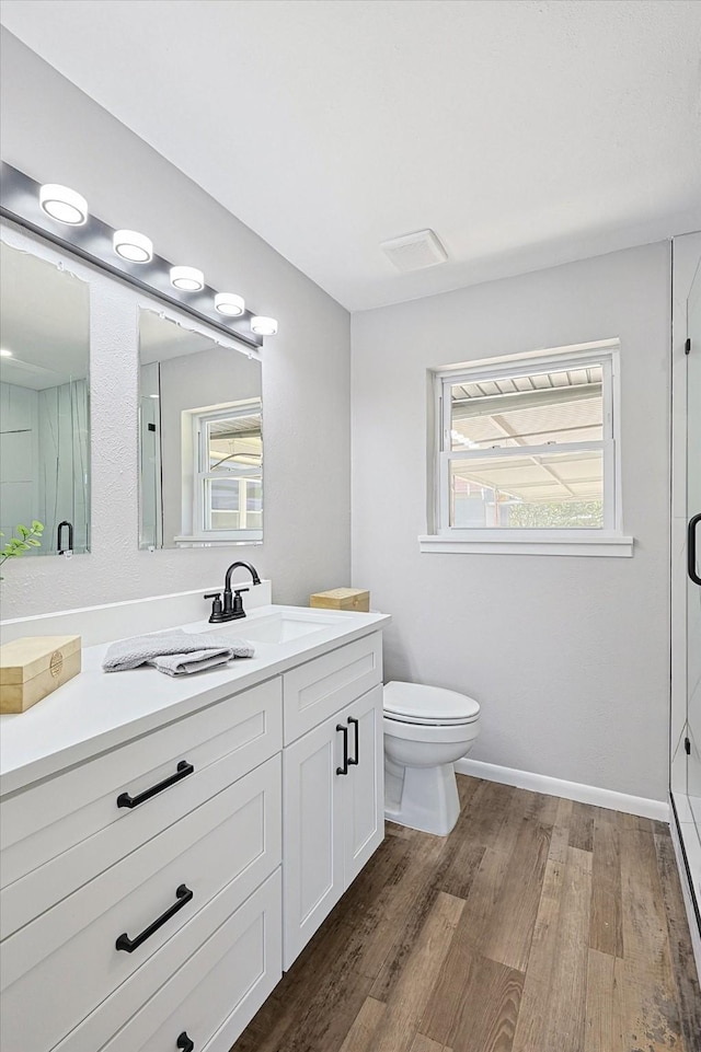 bathroom featuring hardwood / wood-style flooring, a shower with shower door, and a wealth of natural light