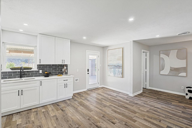 kitchen featuring decorative backsplash, sink, white cabinets, and hardwood / wood-style flooring