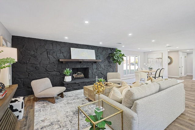 living room featuring light wood-type flooring and a stone fireplace