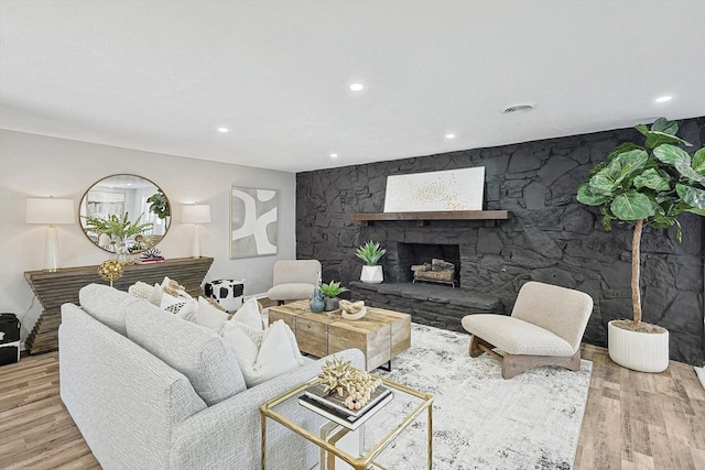 living room featuring a stone fireplace and light hardwood / wood-style floors