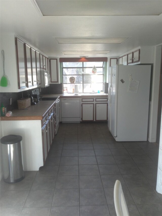 kitchen with dark tile patterned floors and white appliances