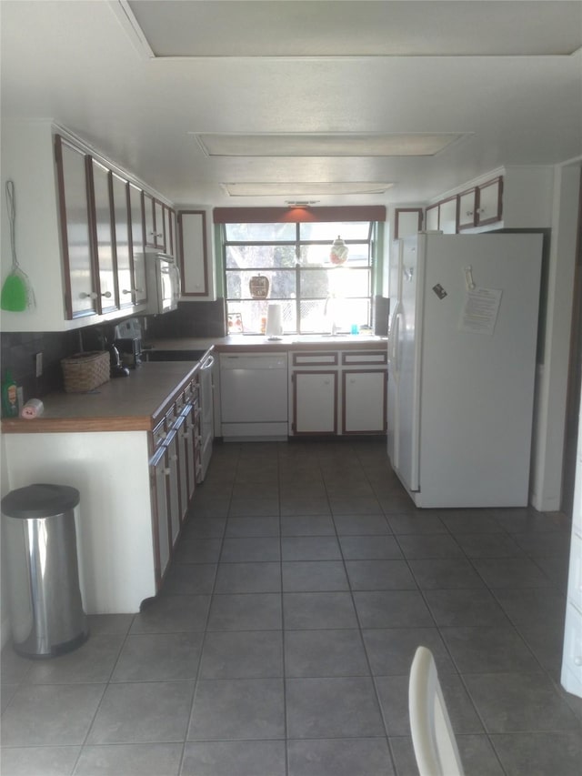 kitchen featuring dark tile patterned floors, tasteful backsplash, and white appliances