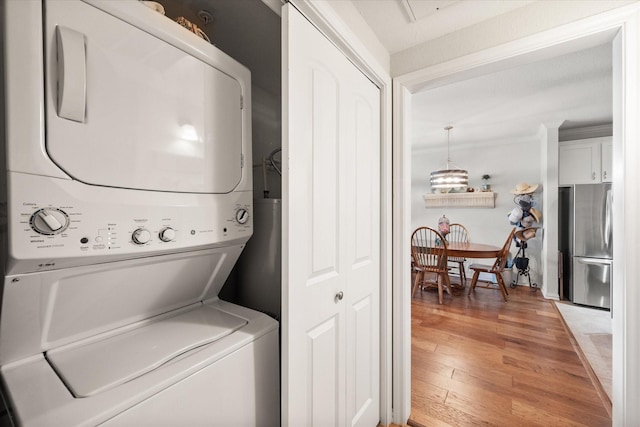 laundry room featuring hardwood / wood-style floors and stacked washer / dryer