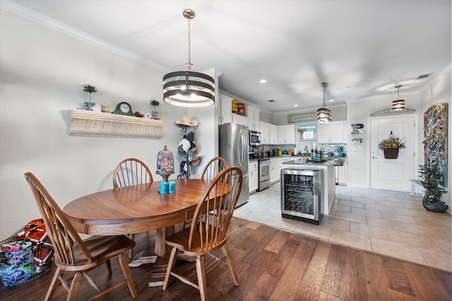 dining space featuring a notable chandelier, light hardwood / wood-style floors, crown molding, and wine cooler