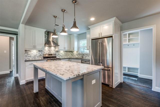 kitchen with a kitchen island, white cabinetry, stainless steel appliances, and wall chimney range hood