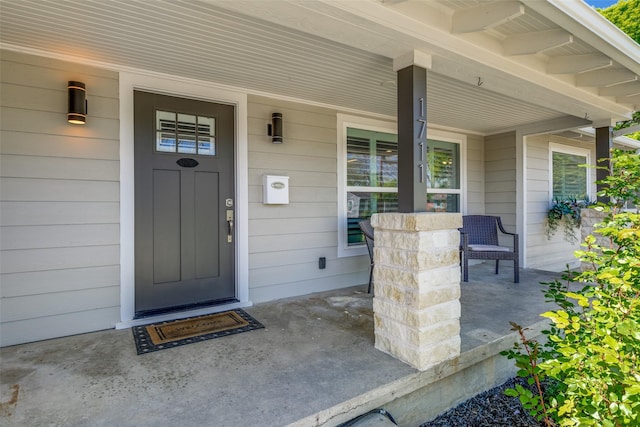 view of exterior entry featuring covered porch