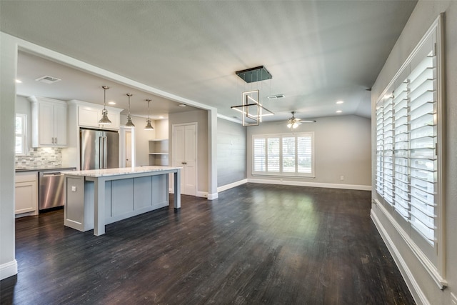 kitchen featuring dark wood finished floors, appliances with stainless steel finishes, open floor plan, a center island, and white cabinetry