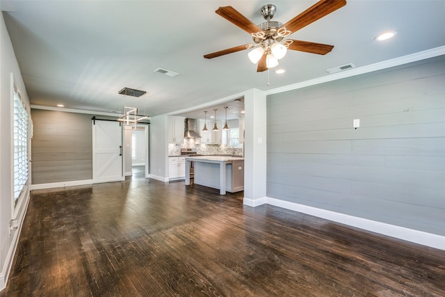 unfurnished living room with dark wood-type flooring, visible vents, ceiling fan, and a barn door