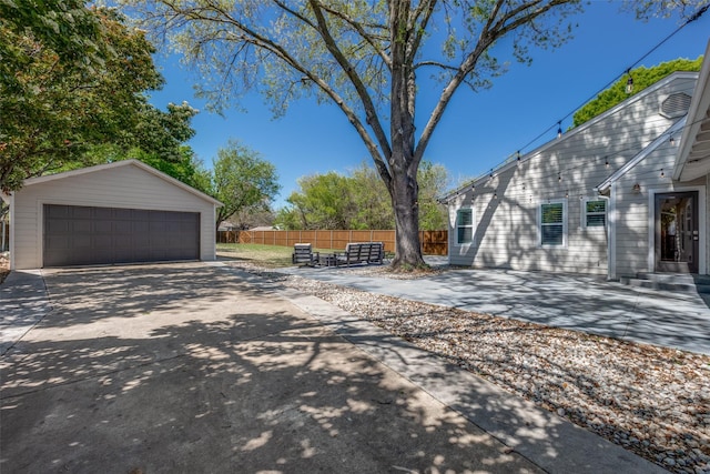 view of yard featuring a detached garage, fence, a patio, and an outbuilding