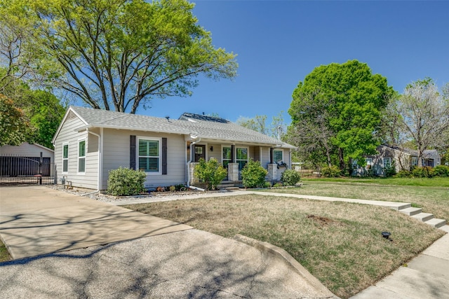 ranch-style home with concrete driveway, a shingled roof, and a front yard