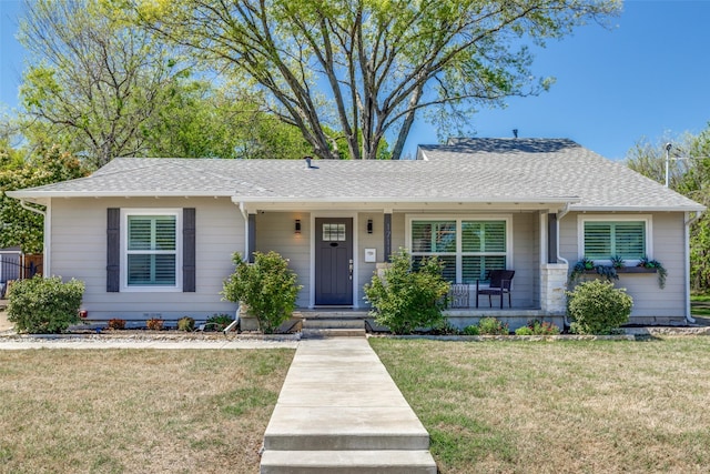 view of front facade featuring covered porch, a front lawn, and a shingled roof