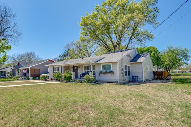 ranch-style house with a porch, central air condition unit, a front yard, and roof with shingles