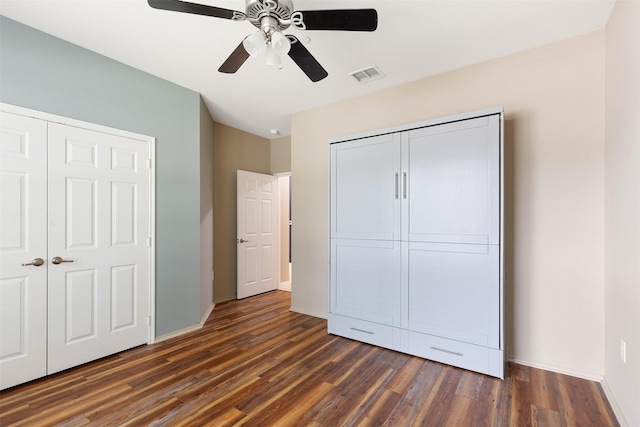 unfurnished bedroom featuring dark wood-type flooring, ceiling fan, and a closet