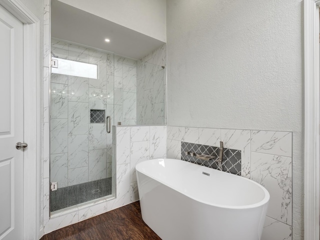 bathroom featuring wood-type flooring, tile walls, and independent shower and bath