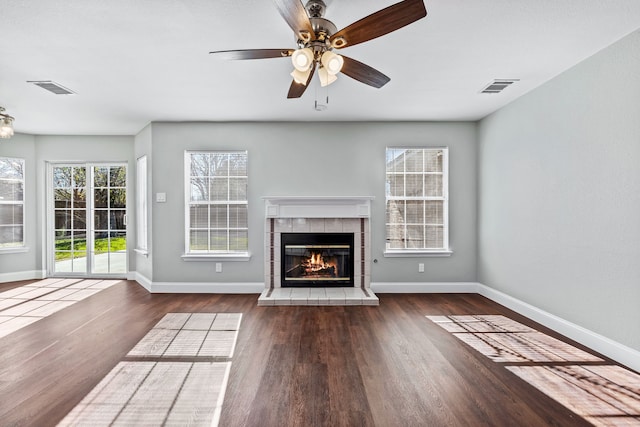 unfurnished living room with dark hardwood / wood-style floors, ceiling fan, and a tile fireplace