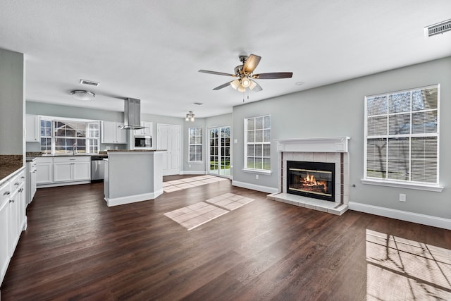 unfurnished living room featuring ceiling fan, dark hardwood / wood-style flooring, and a fireplace