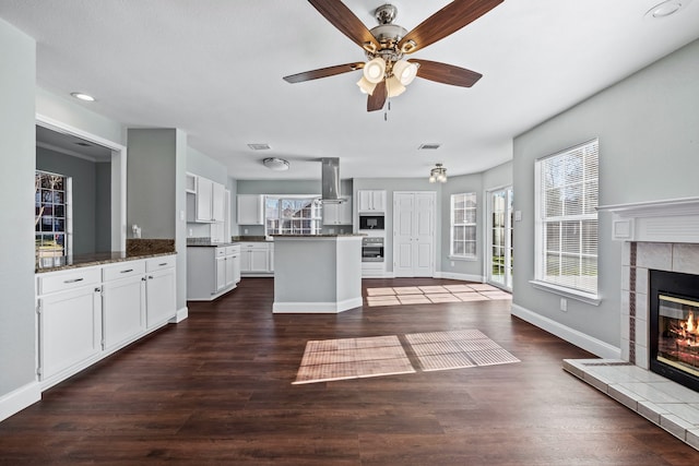 kitchen with white cabinets, oven, a fireplace, and a wealth of natural light