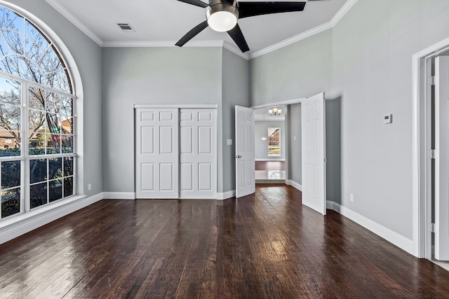 unfurnished bedroom with ceiling fan with notable chandelier, dark wood-type flooring, a closet, and crown molding