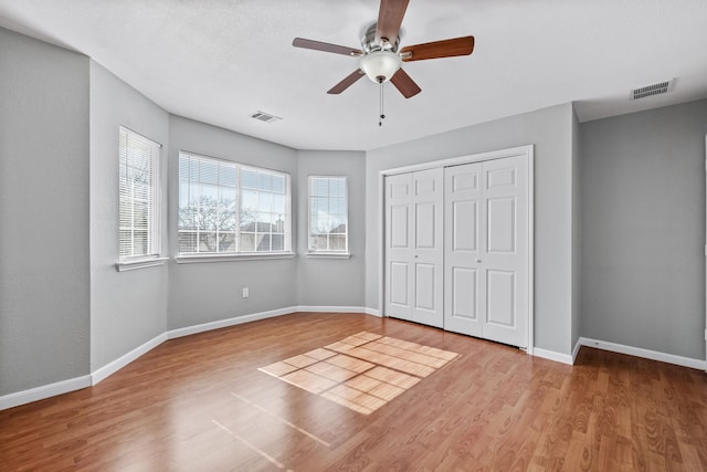 unfurnished bedroom featuring light wood-type flooring, a closet, and ceiling fan