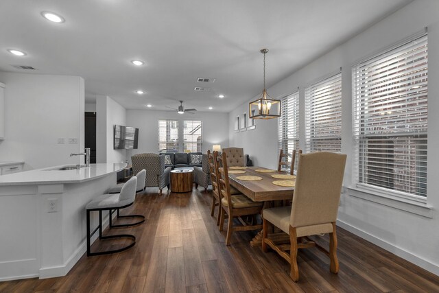 dining space with dark hardwood / wood-style floors, sink, and ceiling fan with notable chandelier