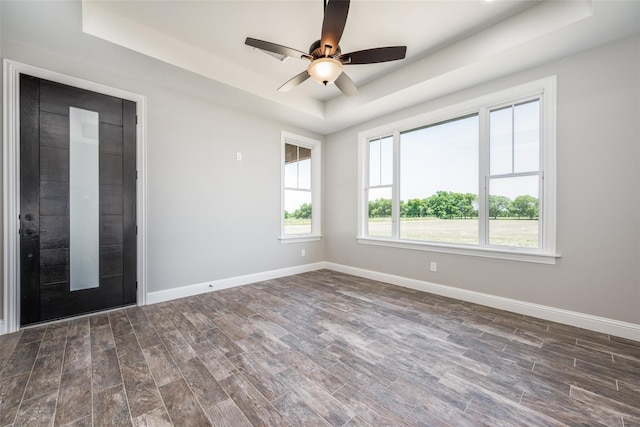 empty room featuring ceiling fan, dark hardwood / wood-style flooring, and a tray ceiling