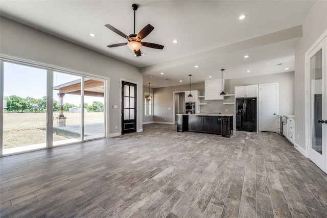 unfurnished living room with wood-type flooring and ceiling fan with notable chandelier