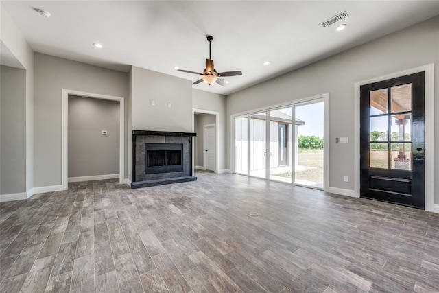 unfurnished living room with ceiling fan, a tiled fireplace, and hardwood / wood-style floors