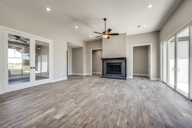 unfurnished living room with french doors, light hardwood / wood-style flooring, and a tiled fireplace