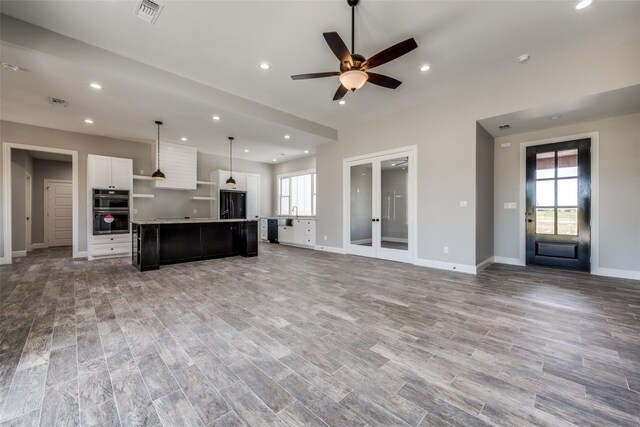 kitchen featuring black refrigerator, a wealth of natural light, white cabinetry, and a kitchen island