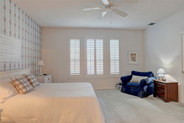 bedroom with ceiling fan, carpet floors, and a textured ceiling