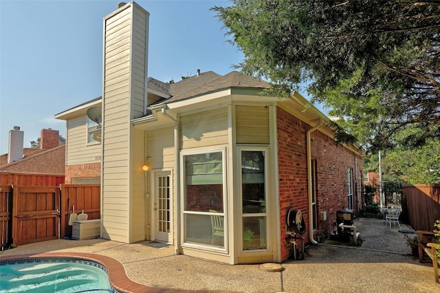 rear view of house featuring a patio area and a fenced in pool