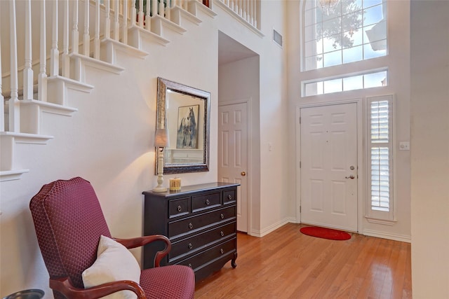 entrance foyer featuring a towering ceiling and light wood-type flooring