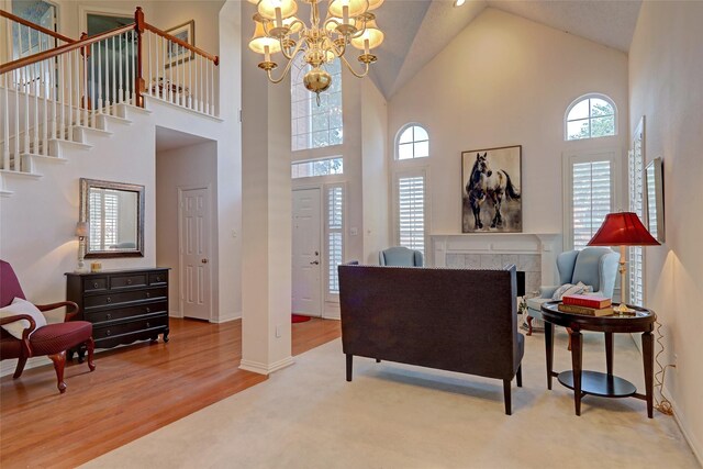 interior space with a fireplace, high vaulted ceiling, wood-type flooring, and a notable chandelier