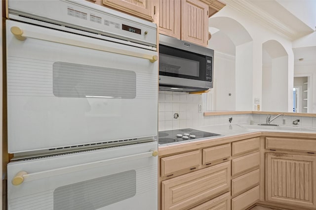 kitchen with light brown cabinetry, backsplash, double oven, sink, and electric cooktop