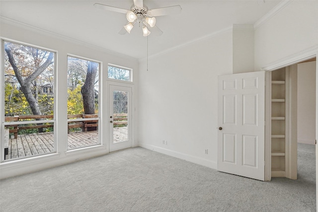 carpeted spare room featuring ceiling fan, ornamental molding, and a wealth of natural light