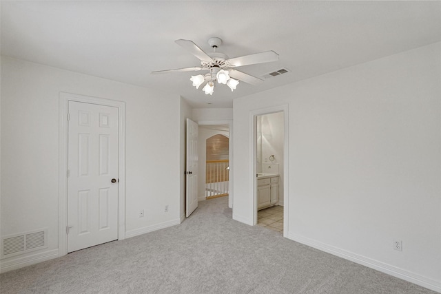 unfurnished bedroom featuring connected bathroom, ceiling fan, and light carpet