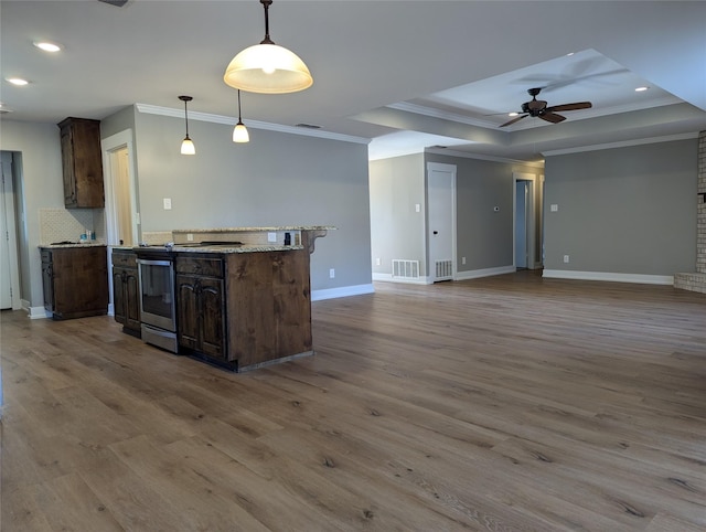 kitchen with pendant lighting, a raised ceiling, crown molding, and hardwood / wood-style floors