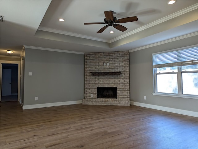 unfurnished living room with a raised ceiling, ceiling fan, a fireplace, and hardwood / wood-style flooring