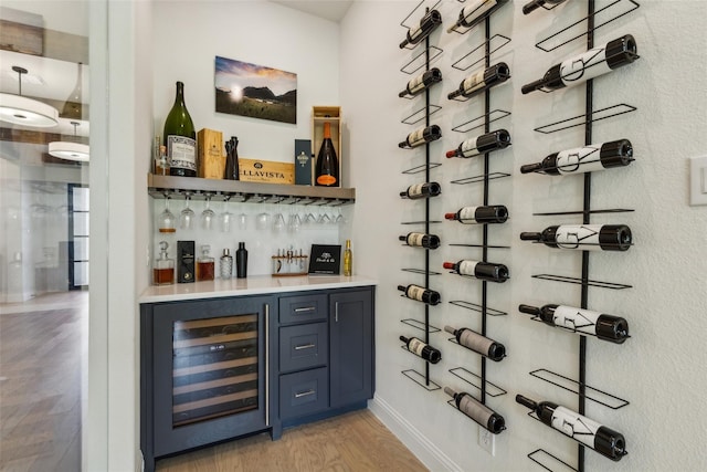 wine room with bar, wine cooler, and light hardwood / wood-style flooring