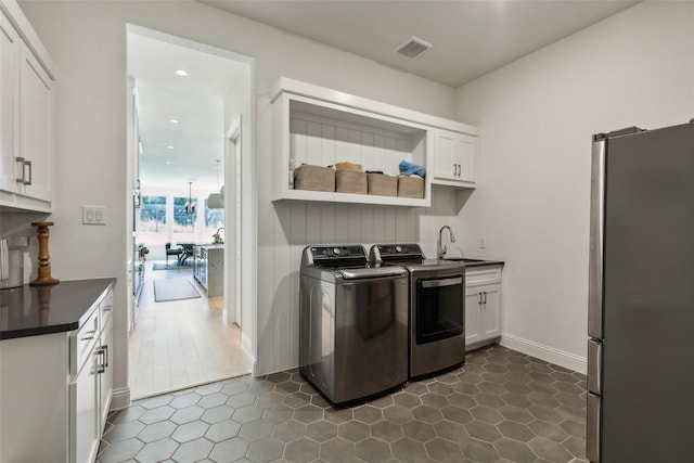 clothes washing area featuring cabinets, separate washer and dryer, and sink