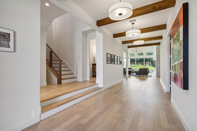 corridor with hardwood / wood-style floors, beamed ceiling, and an inviting chandelier