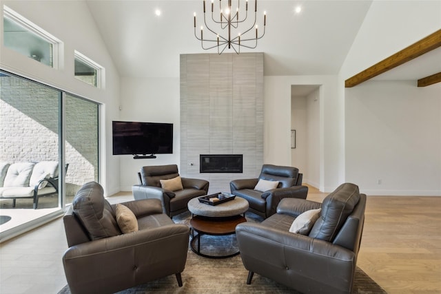 living room with a tiled fireplace, a high ceiling, a notable chandelier, and light wood-type flooring