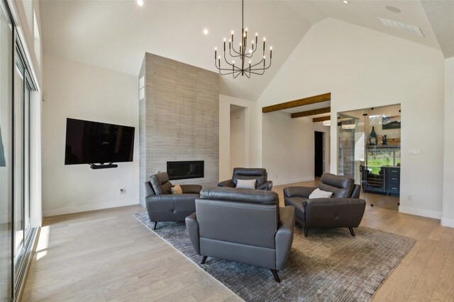 living room featuring high vaulted ceiling, a tile fireplace, and light wood-type flooring