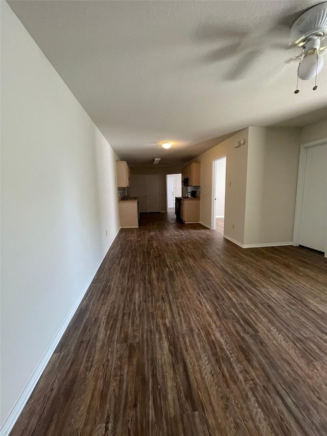 unfurnished living room featuring ceiling fan, dark hardwood / wood-style flooring, and a textured ceiling